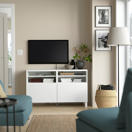 Sala de estar moderna con mueble de TV BESTÅ, TV de pantalla plana, sofá turquesa, lámpara y cuadros enmarcados.