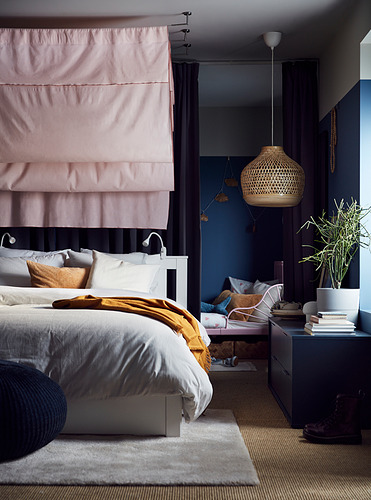 Dormitorio moderno con cama SONGESAND, dosel rosa claro, paredes azul oscuro, colgante tejido ligero y textiles acogedores.