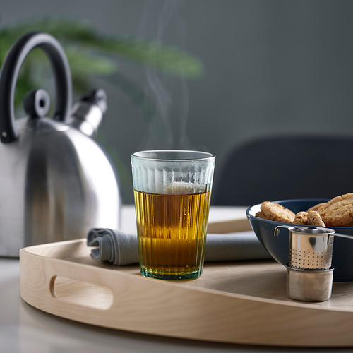Bandeja con té, infusor, galletas, servilleta y hervidor de agua.