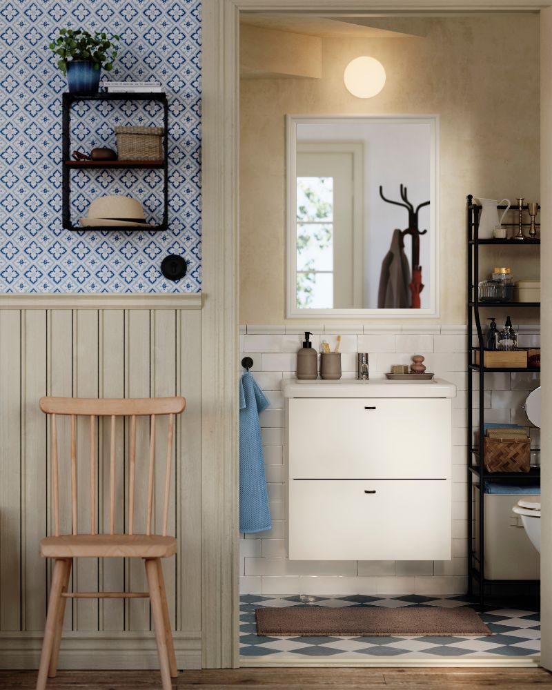 A white ENHET/TVÄLLEN wash-stand with drawers is on a subway-tiled wall in a traditional-styled half bath under a staircase.