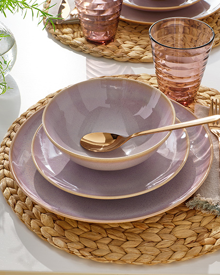 Several  light pink FÄRGKLAR plates  with golden spoon on a table