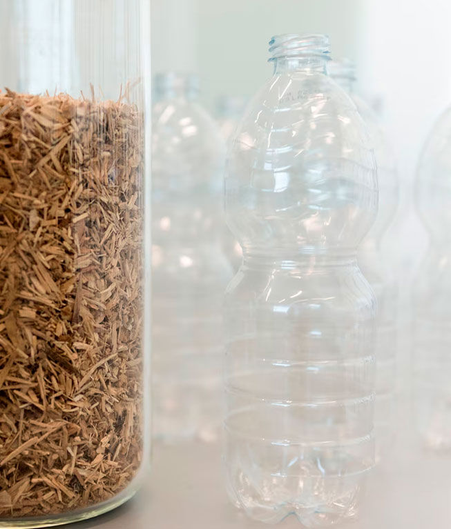 Glass bottle with wood shavings on left; several empty, clear plastic bottles on right.