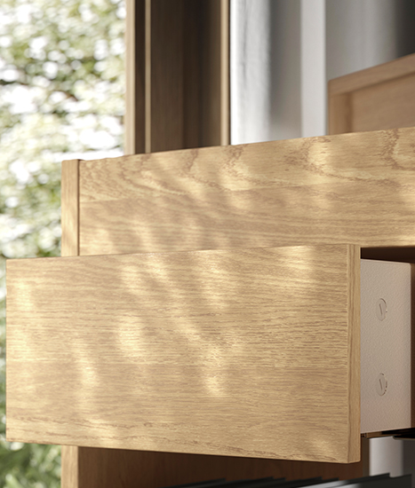 Close-up of a partially open light wood drawer with a white interior frame, with natural light coming through the window.