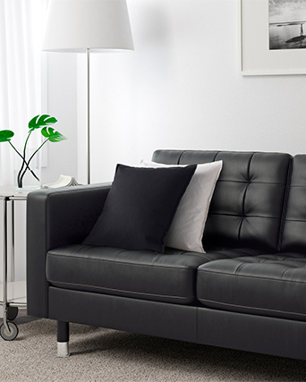 Una sala de estar con un sofá LANDSKRONA de 2 plazas con cojines encima, una alfombra KNARDRUP debajo y una lámpara de piso NYFORS al fondo.