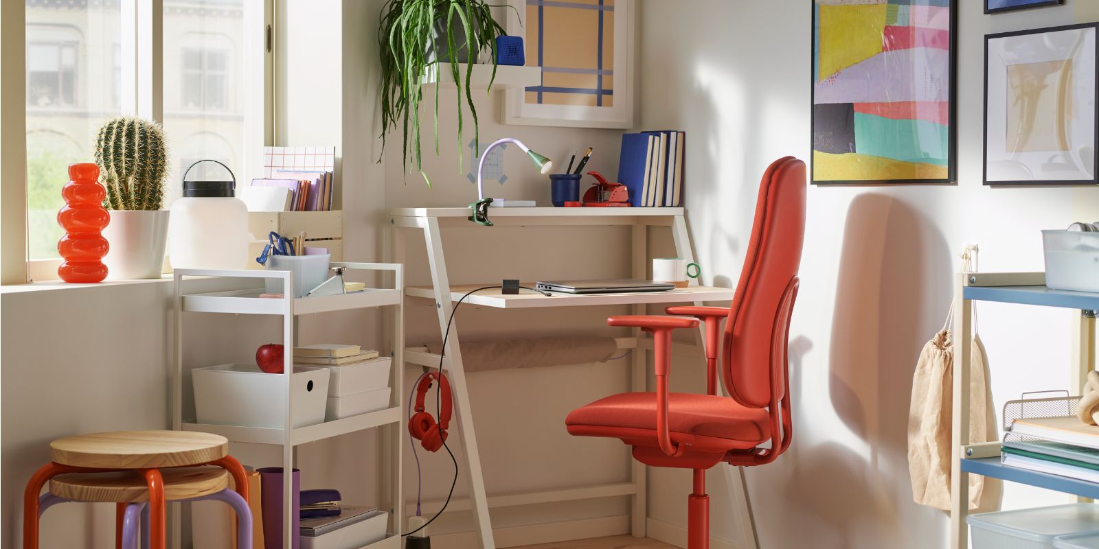 Bright and modern study space with white desk, red ergonomic chair, and colorful decor, perfect for working or studying at home.