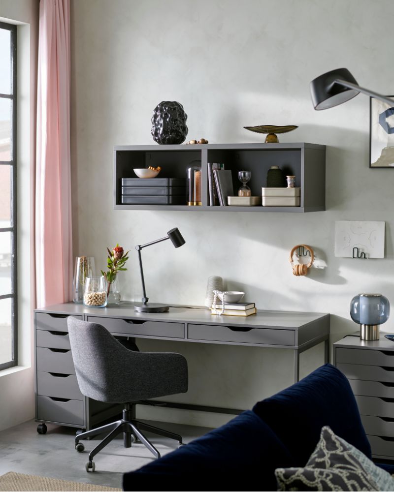 Home office with gray desk, swivel chair and wall shelving, ideal for a modern and organized workspace.