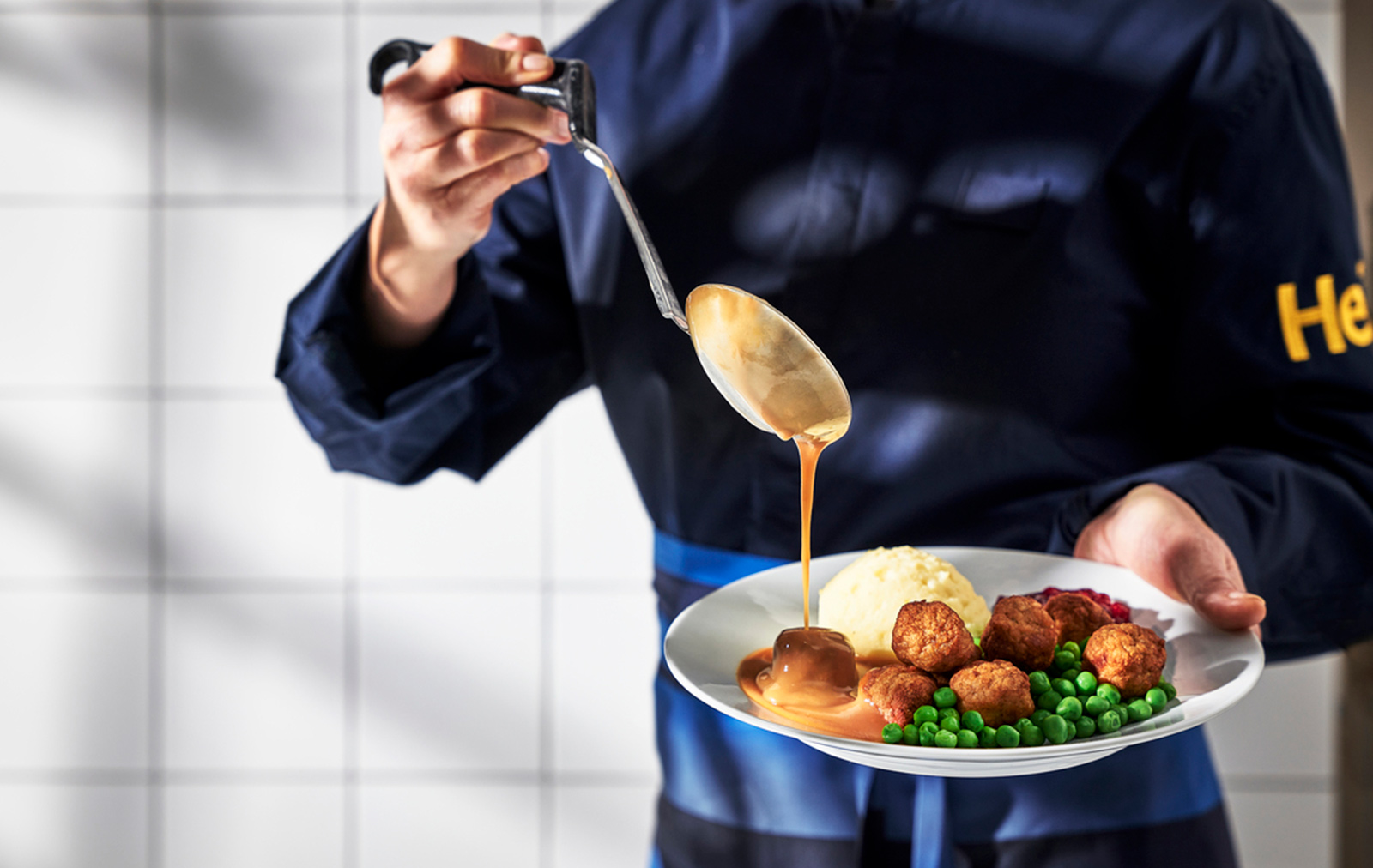 Chef drizzling IKEA meatballs with sauce.