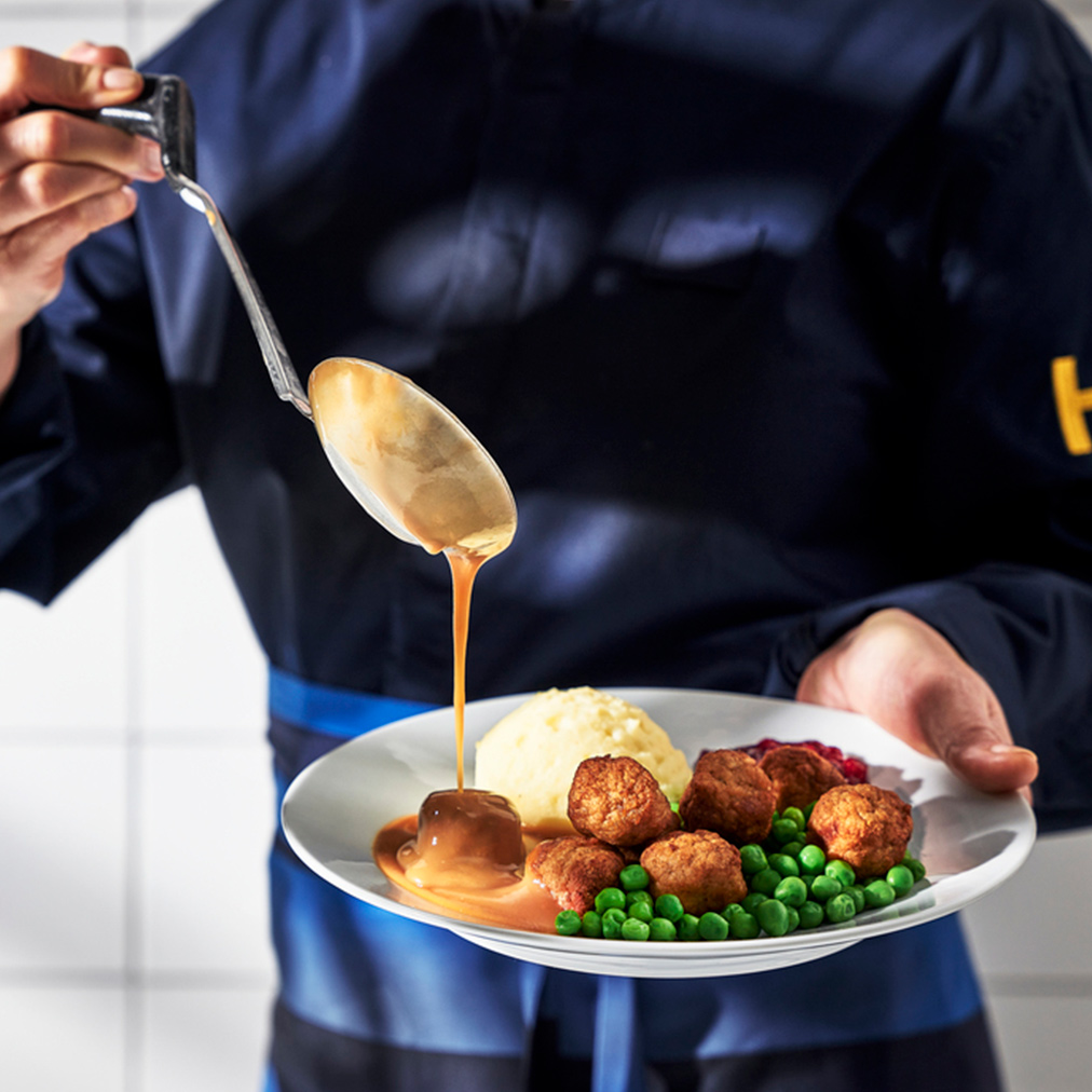Chef drizzling IKEA meatballs with sauce.