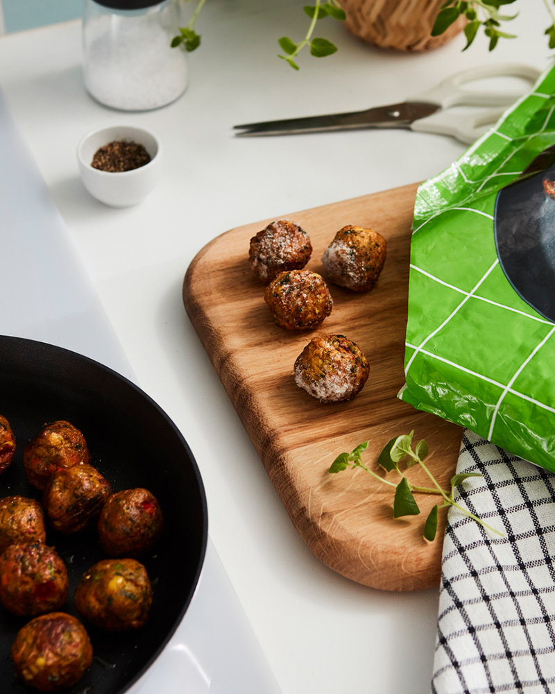 IKEA plant-based protein meatballs on a skillet and a wooden board.