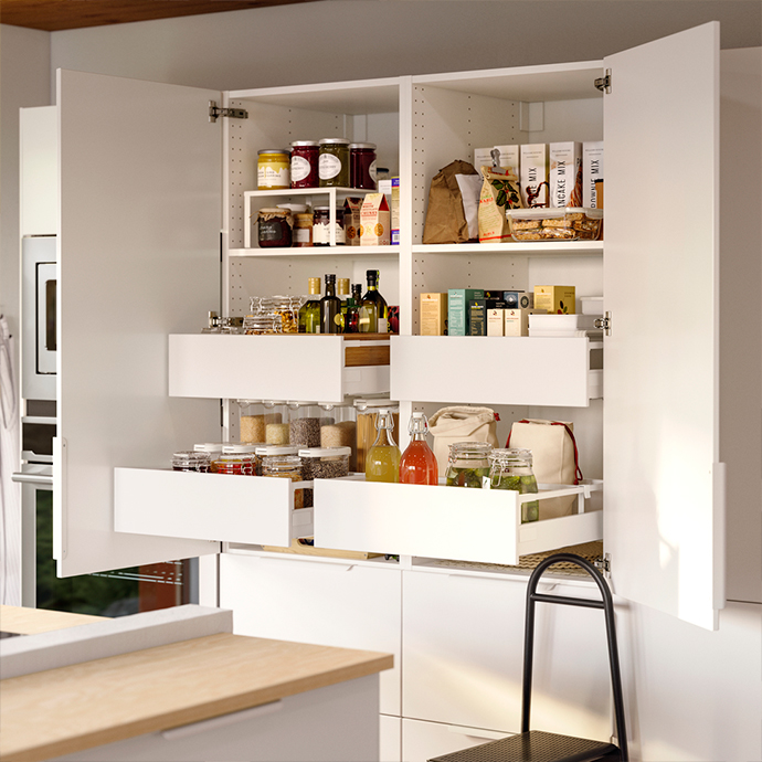 Interior de un armario de cocina blanco con estantes y soluciones extraíbles UTRUSTA, organizando alimentos y botellas. Maximiza el espacio de tu despensa.