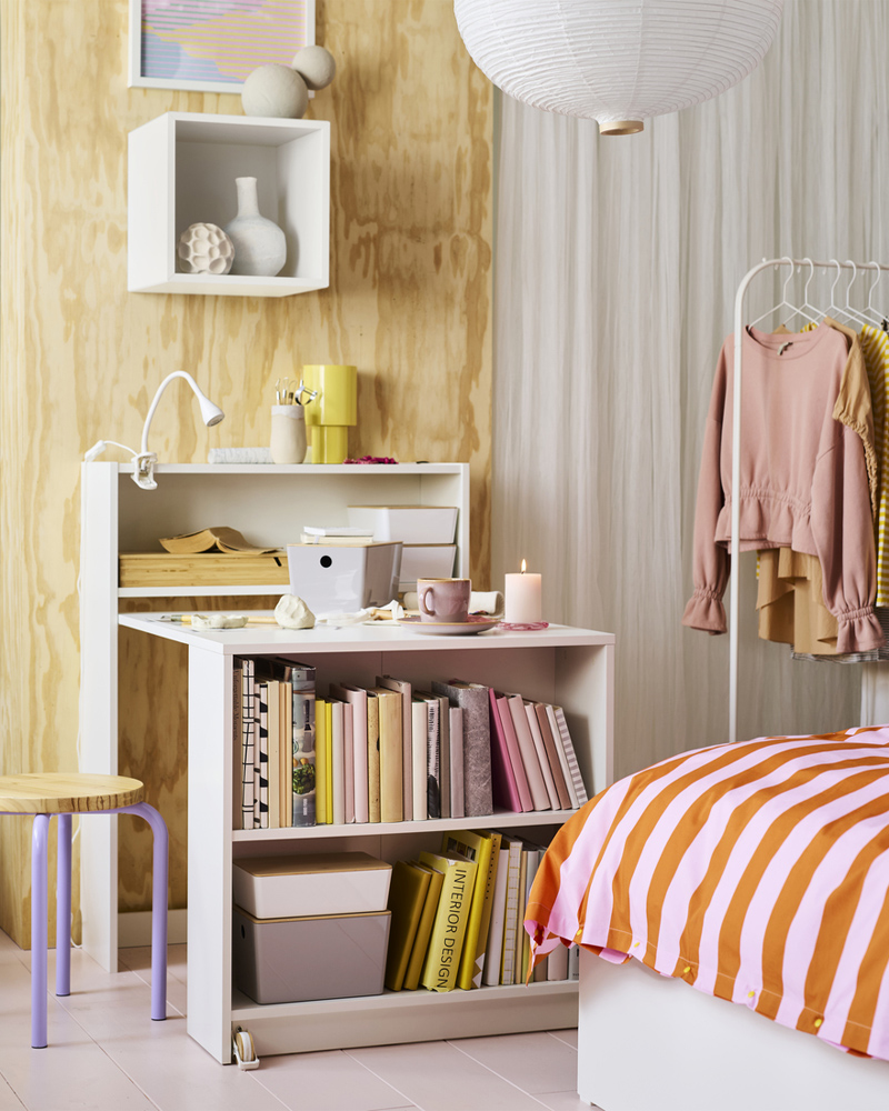 A lilac/pine DOMSTEN stool next to a white BILLY bookcase with foldable table. The table has various craft materials on top.