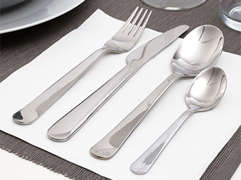 Stainless steel cutlery set, including a fork, knife, spoon, and teaspoon. They are placed on a white napkin and a gray placemat.
