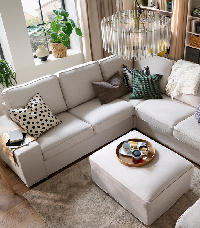 living room with sofa, footstool, decorated with a chandelier, rug, cushions, etc.