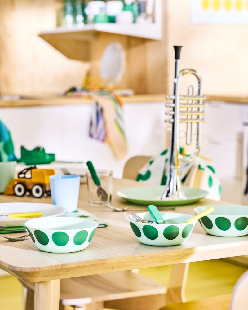 OFTAST bowls with green spot motif on a family dinner table in a Scandinavian modern kitchen.