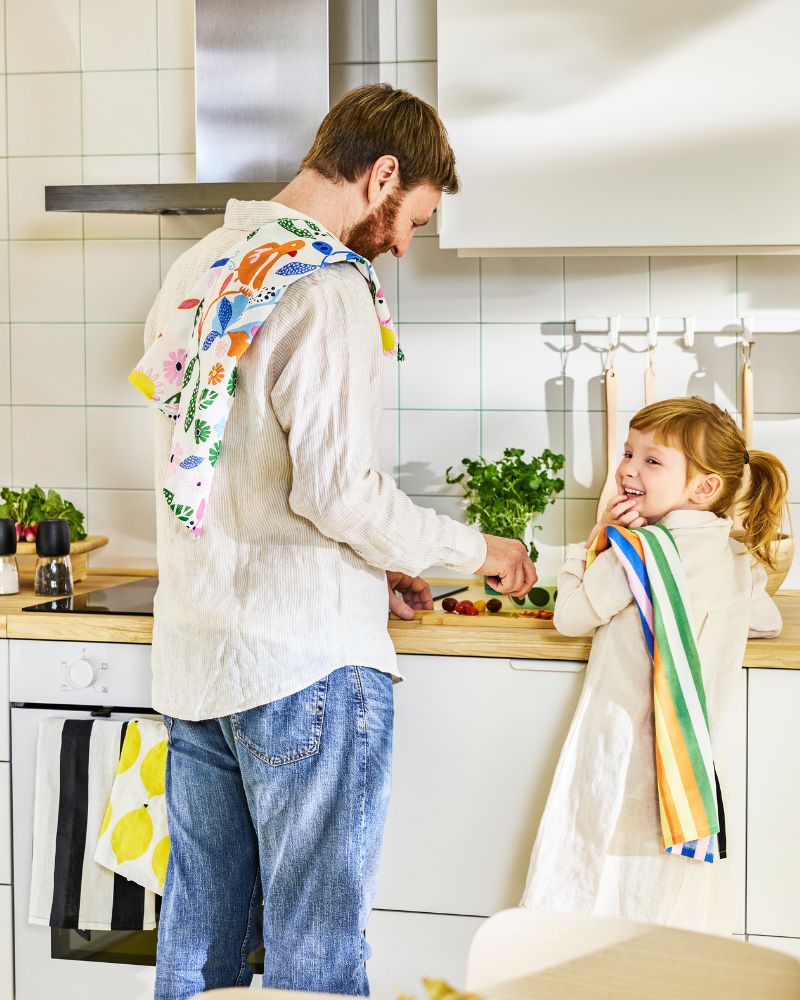 Father and daughter prepping a meal with bright linen RINNIG tea towels in a Scandinavian modern kitchen.