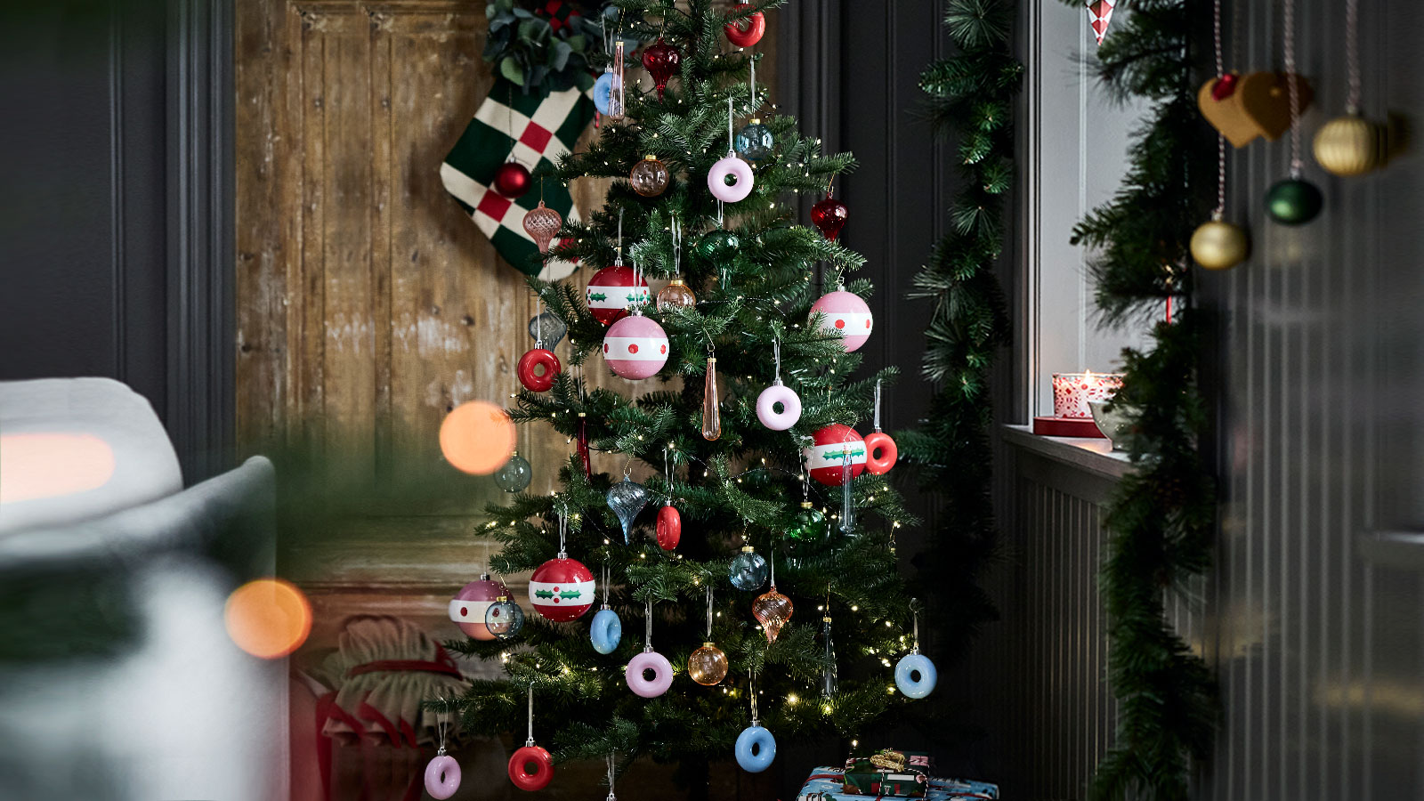 A Christmas tree is decorated with playful VINTERFINT tree ornaments shaped like donuts hanging on its branches.