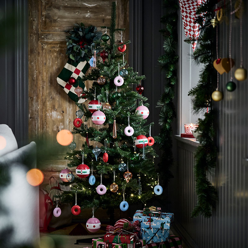 A Christmas tree is decorated with playful VINTERFINT tree ornaments shaped like donuts hanging on its branches.