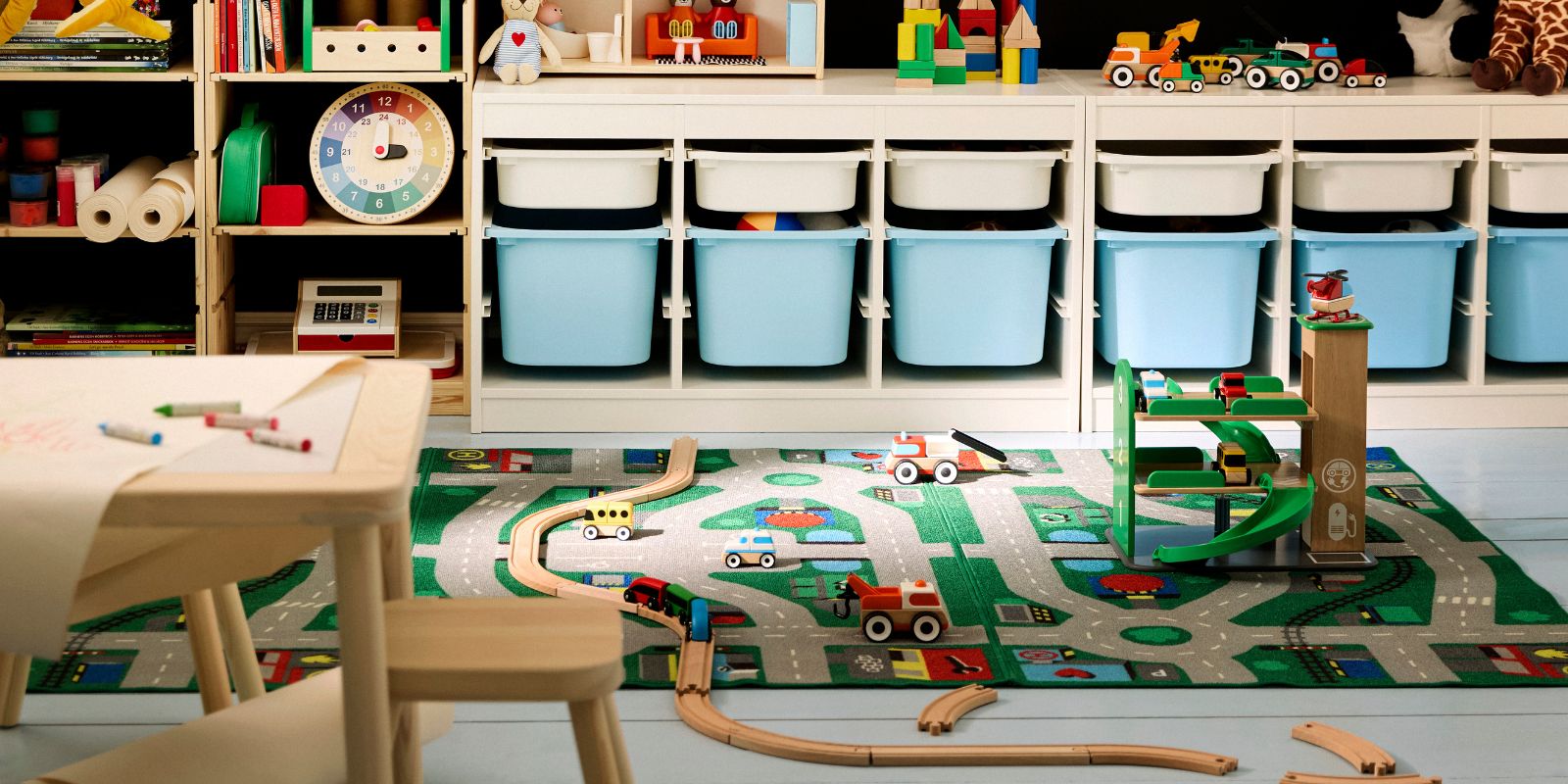 Colorful kids' playroom with black walls, a light wood desk, and toy storage. Blue and white bins for toys.