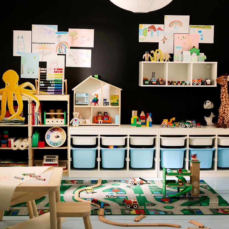 Colorful kids' playroom with black walls, a light wood desk, and toy storage. Blue and white bins for toys.