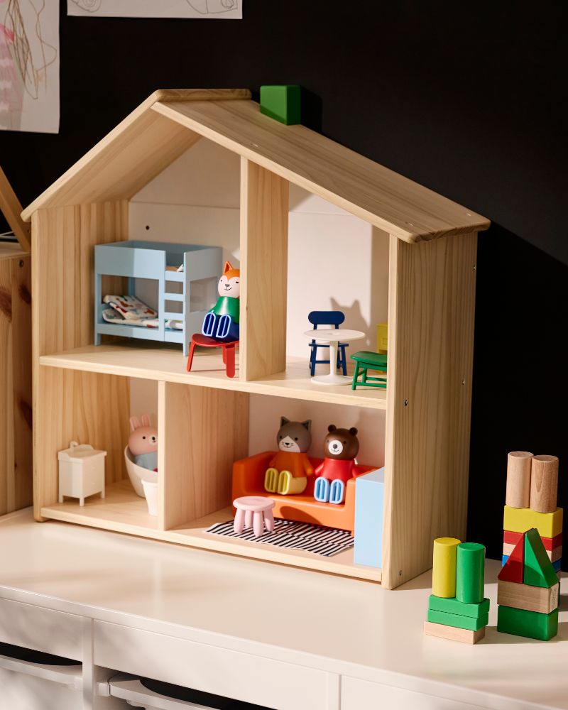 A natural wood dollhouse with colorful furniture and animal figures, including a blue bunk bed and orange couch.