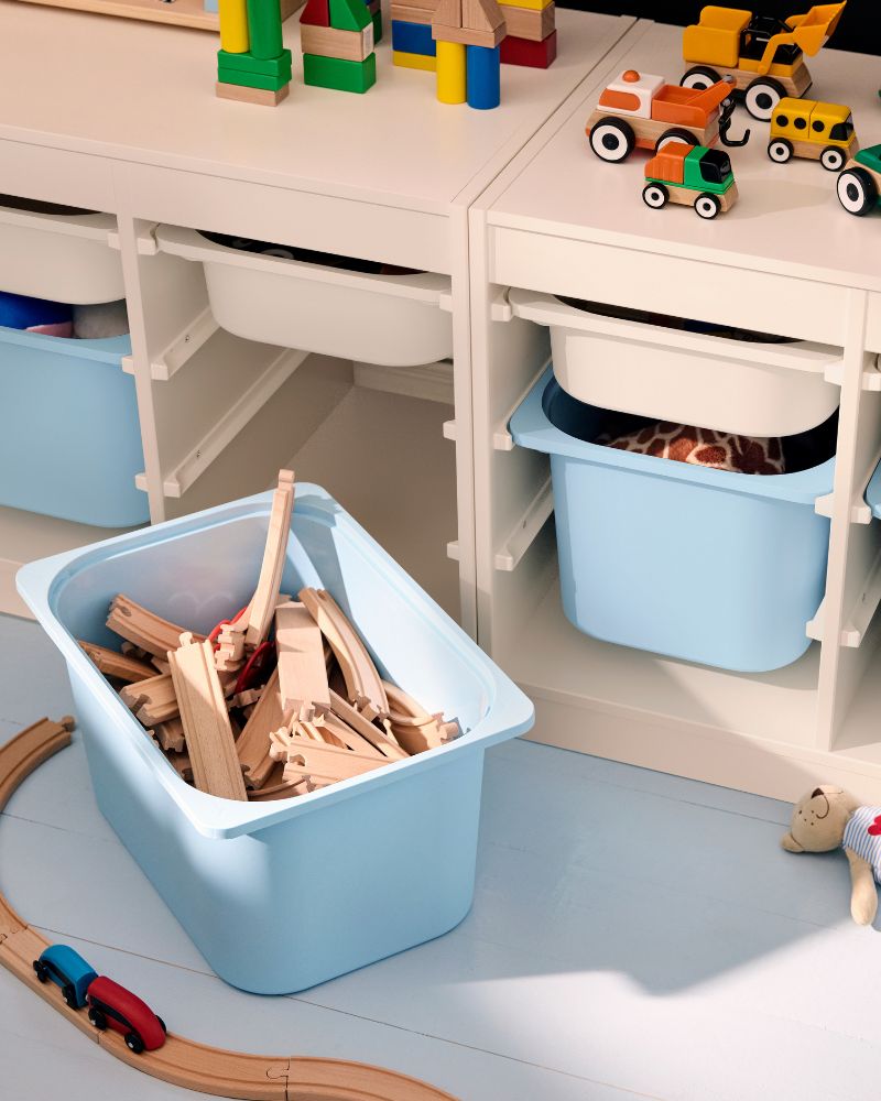 A light blue bin filled with wooden train tracks, next to other white and blue storage bins.