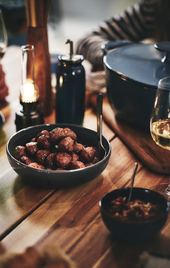 A GLADELIG bowl of HUVUDROLL plant balls on a dining table at a dinner party