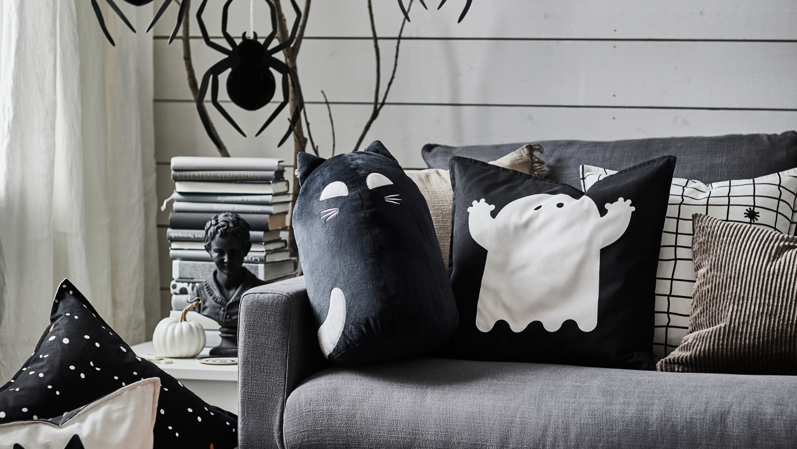 Several KUSTFYR cushions rest on a sofa. In front, a soft toy are placed neatly.