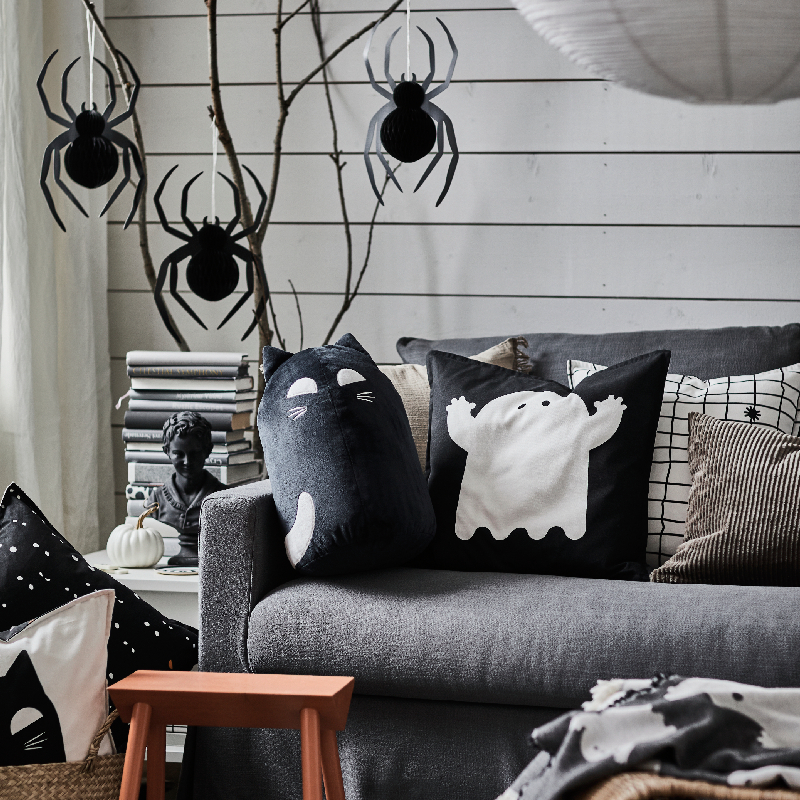 Several KUSTFYR cushions rest on a sofa. In front, a soft toy are placed neatly.