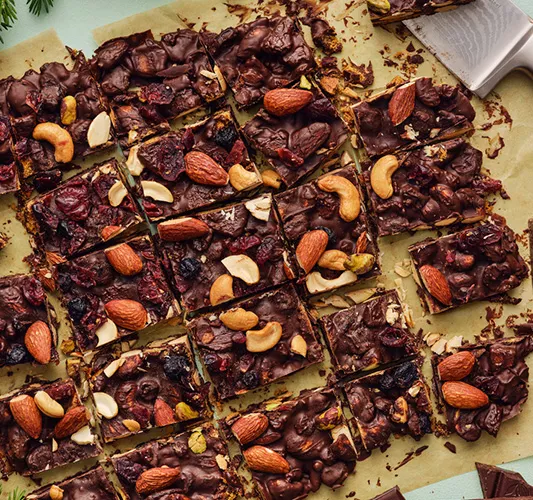 Close-up of a chocolate nut bark with almonds and cashews, cut into small squares and ready to serve.