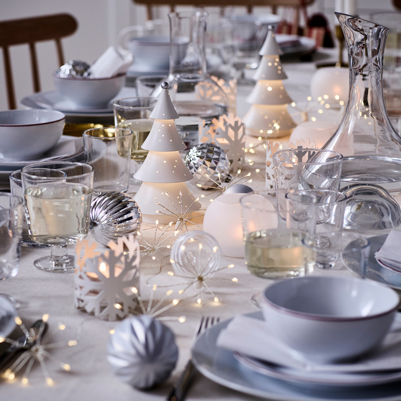 Mesa navideña festida de blanco con lámparas de mesa y vajilla elegante
