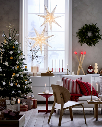 Salón navideño con árbol decorado, lámparas en forma de estrella en la ventana y detalles rojos en los textiles
