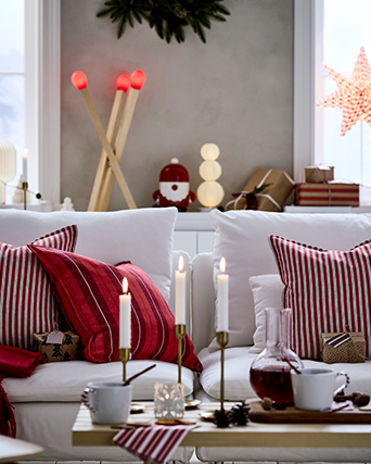 Salón navideño con candelabro encendido, textiles rojos sobre el sofá