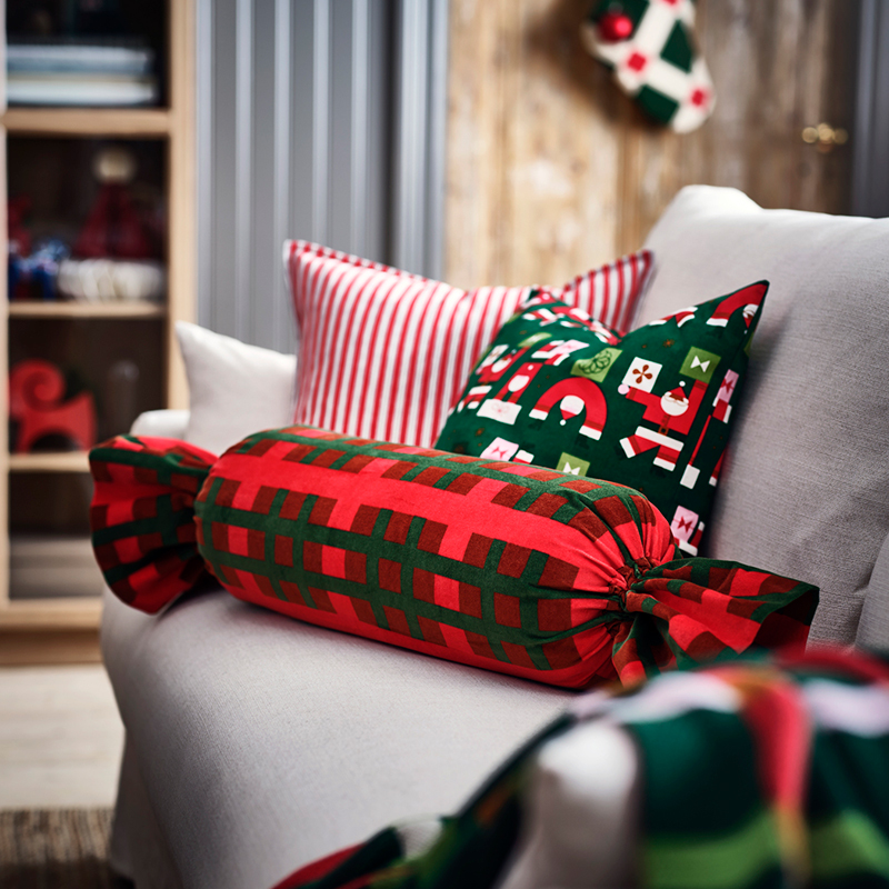Cojines de colores rojos y verdes con motivos navideños sobre un sofá gris