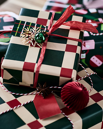 Regalos envueltos en papel de regalo a cuadros verdes y rojos, coronado con un lazo rojo