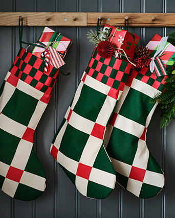 Tres calcetines navideños, en colores verdes y rojos, colgados de un perchero y llenos de regalos