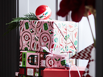 Regalos envueltos en papel con motivos rojos y decorados con bolas de árbol navideño