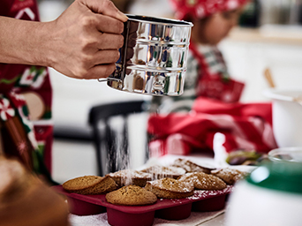 Hombre espolvoreando con azúcar unas magdalenas recién hechas