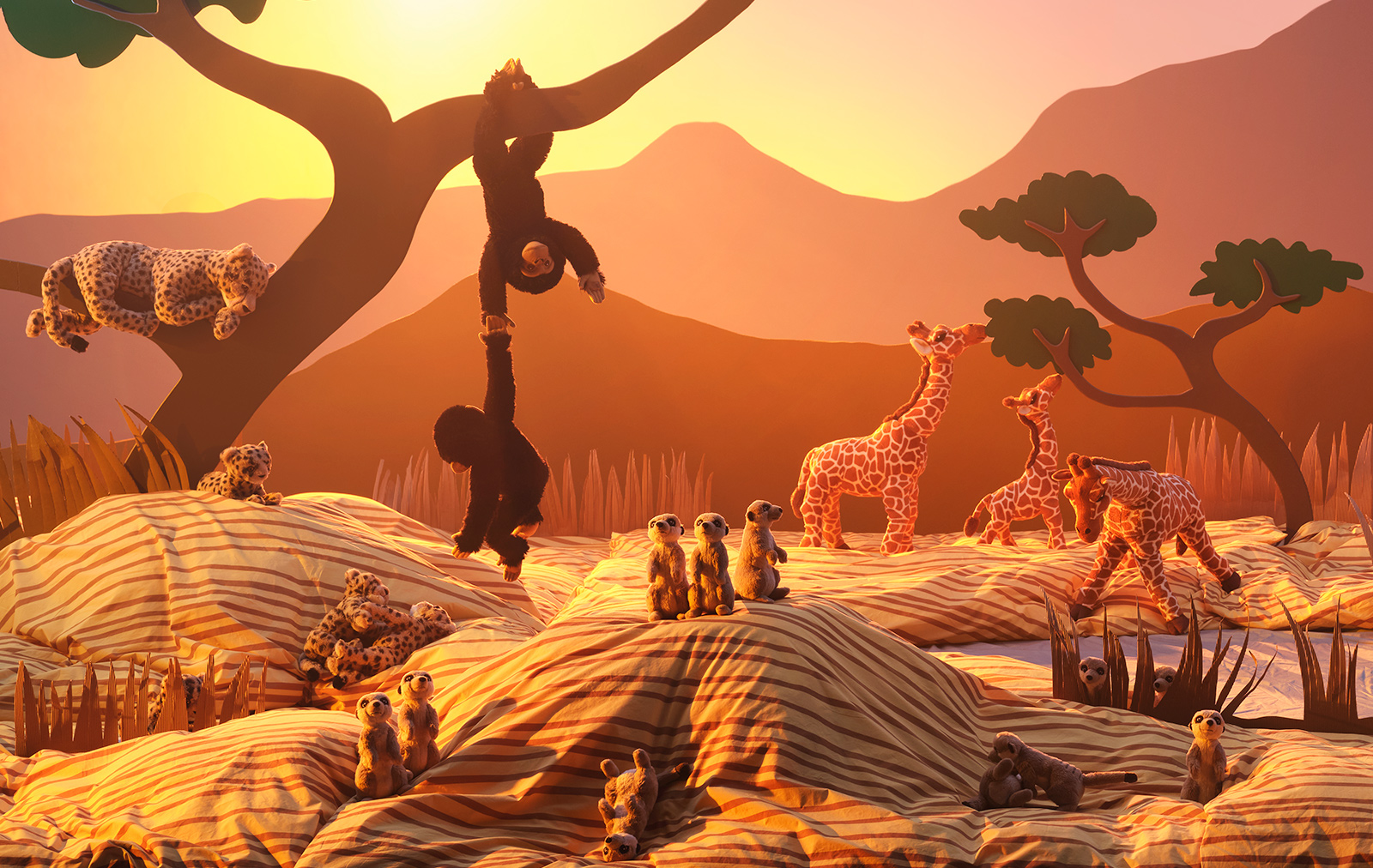 A sunlit savannah made from cardboard cutouts and duvet covers and pillowcases is filled with SANDLÖPARE soft toy animals.