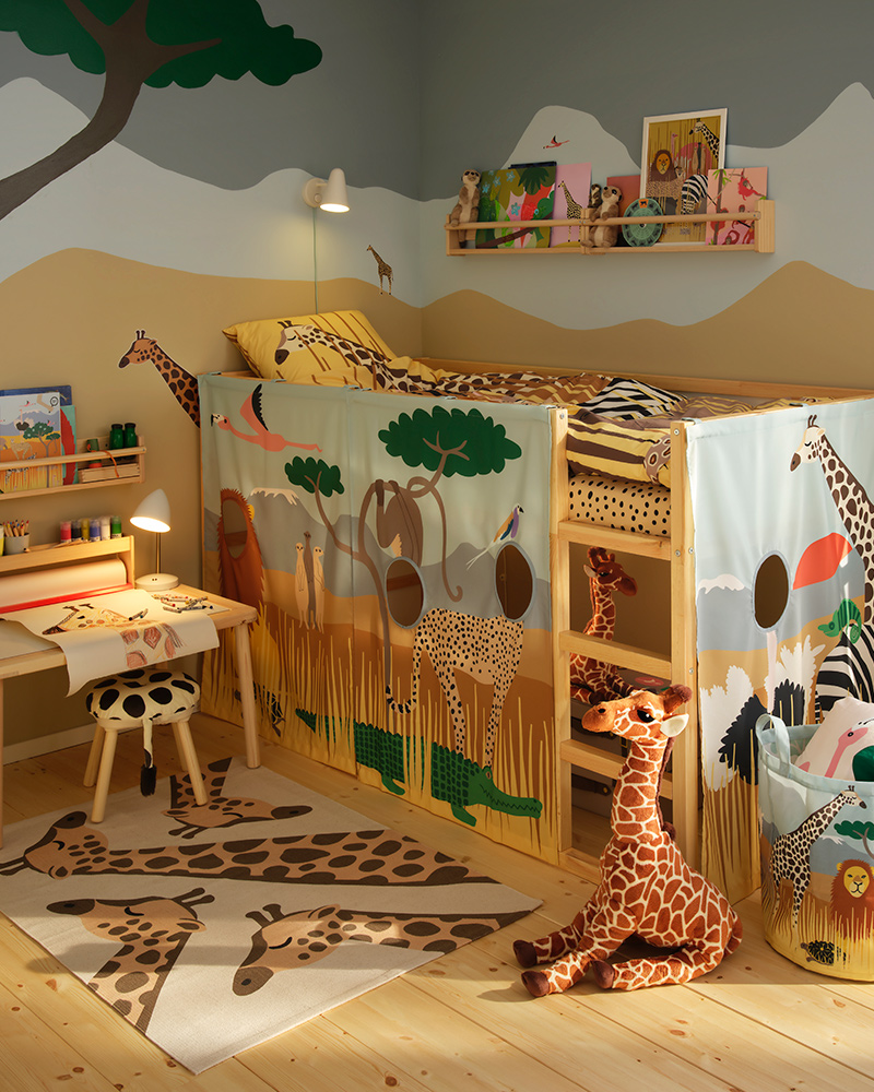 Children’s room filled with savannah themed toys from the SANDLÖPARE collection with giraffes on both rug and bedding.