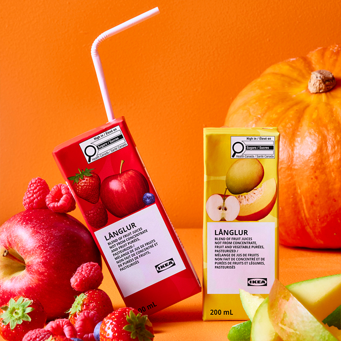 LÄNGLUR fruit juice cartons in red berry and yellow apple flavors with fresh fruits and pumpkin on orange background
