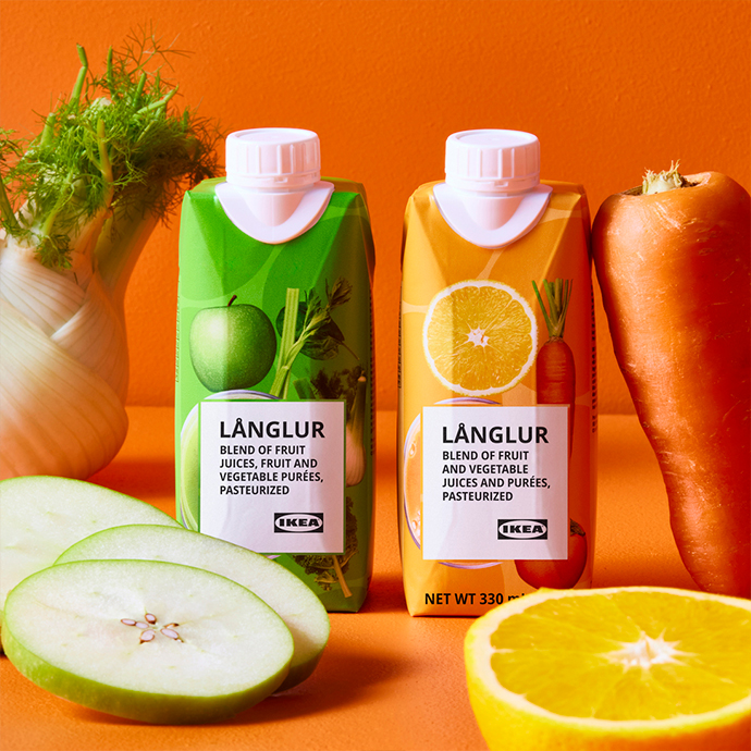 Two LÄNGLUR juice cartons in green and orange packaging next to fresh carrots and sliced apple on orange background