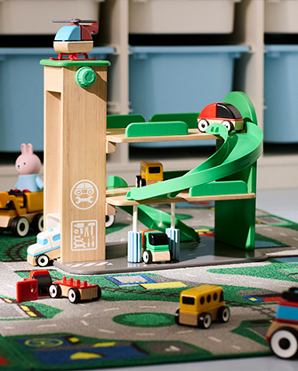 Garaje de madera con rampa en espiral y elevador para coches. Coches de juguete sobre alfombra con señales de tráfico