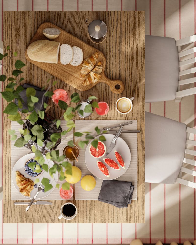 An eagle-eye’s view of an ÅLHULT table with a bench and chairs. The table is set for a brunch with bread, coffee and fruit.