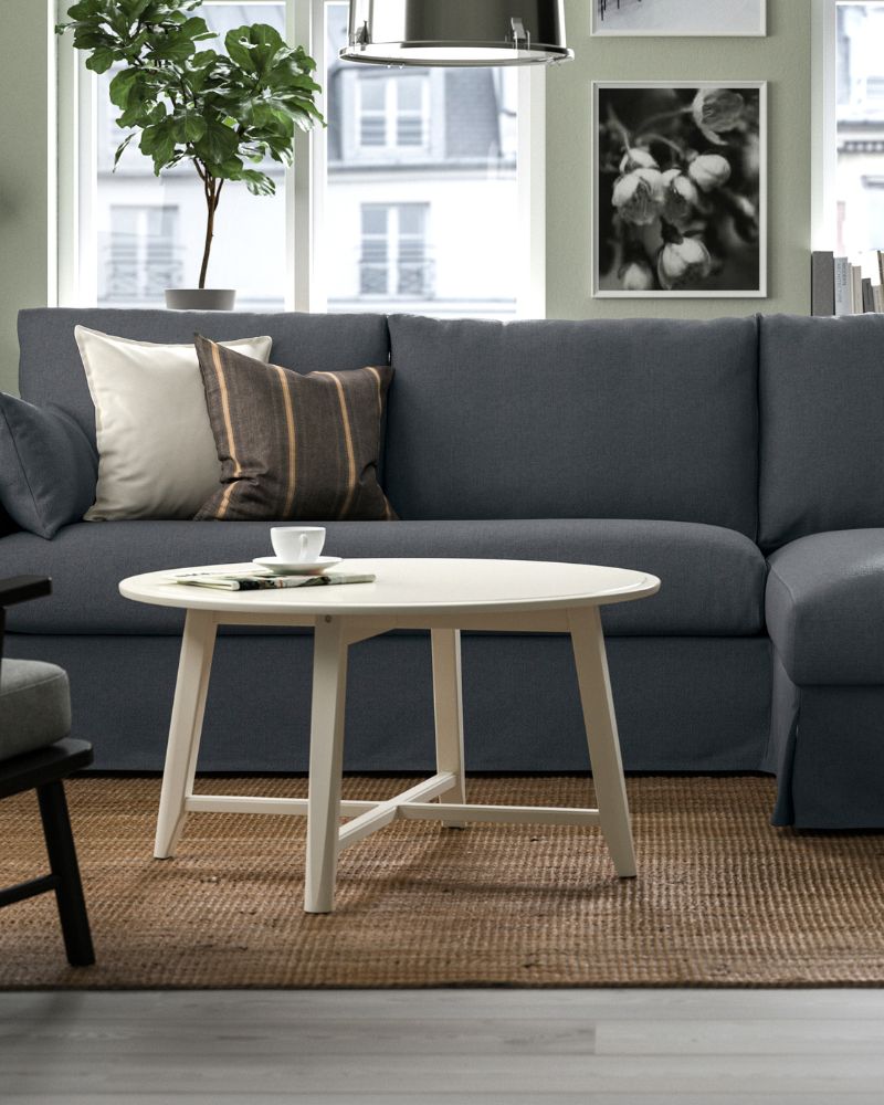 A KRAGSTA coffee table stands in front of a grey HYLTARP 3-seat sofa with chaise longue in a bright living room.