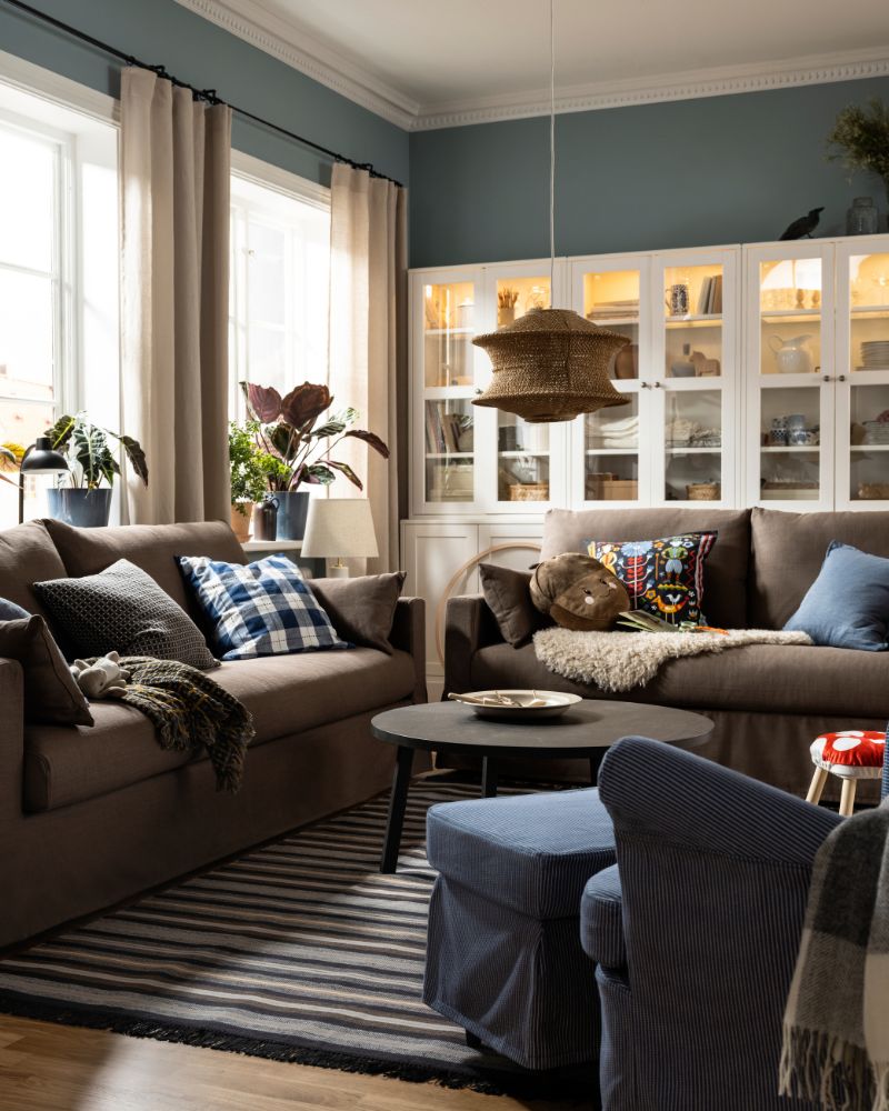 Two HYLTARP sofas with a lot of extra cushions on them stand near a dark brown STOCKHOLM 2025 coffee table on a RÅVAROR rug.