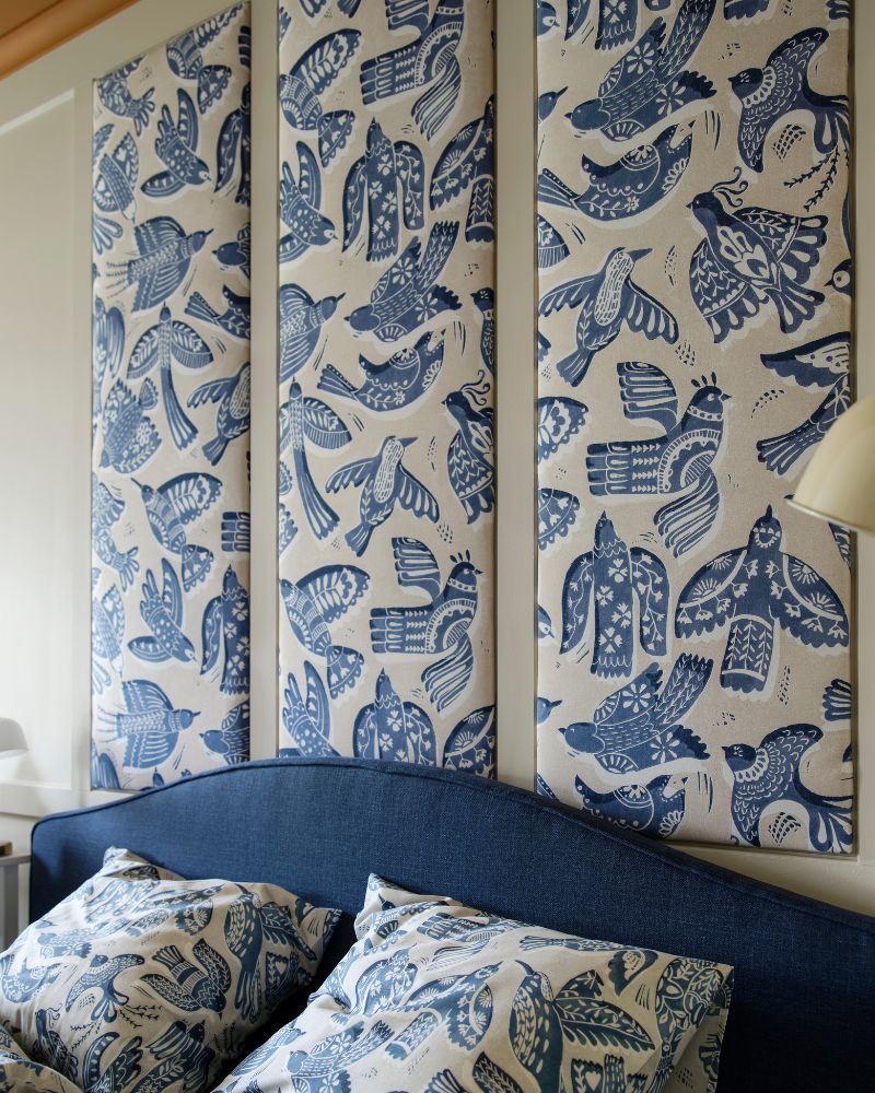 A light grey/blue BITTERSÖTA duvet cover and pillowcase set on a bed beneath wall panels made from BITTERSÖTA pre-cut fabric.