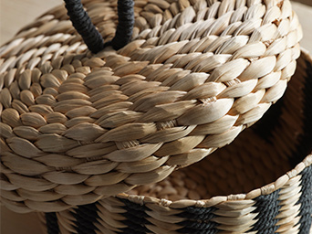 Una caja MÄVINN con tapa. La técnica de trenzado detallada es visible, al igual que el lazo de algodón negro en la parte superior de la tapa.