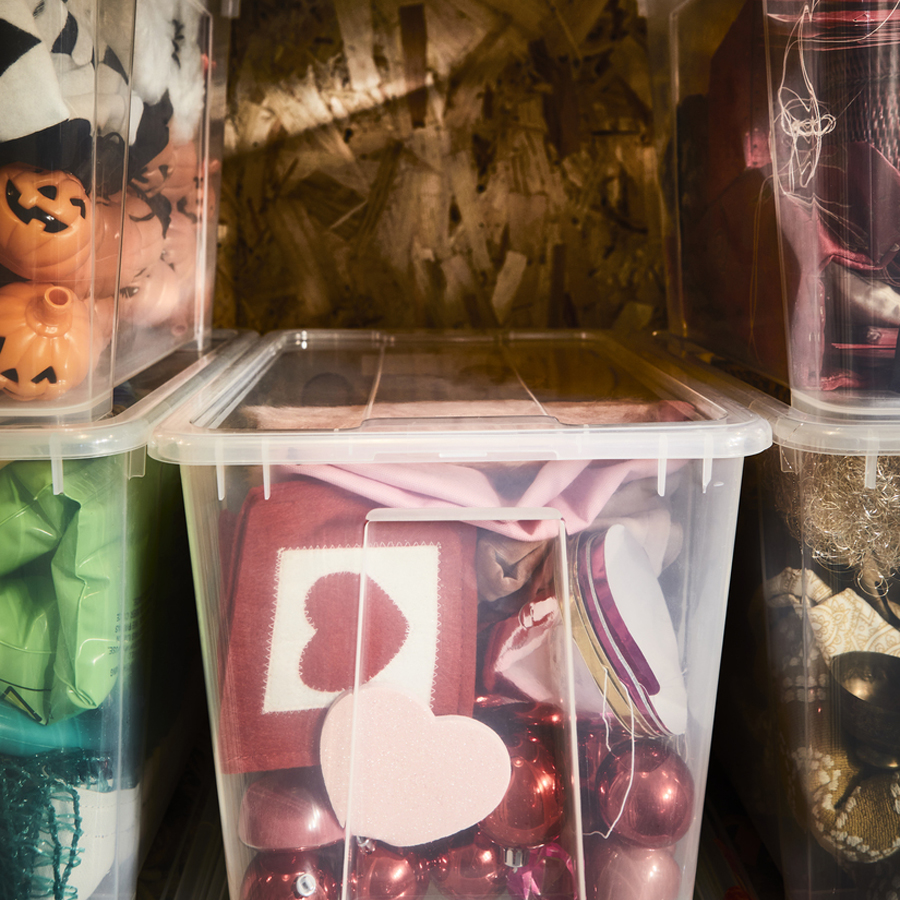Clear storage boxes containing seasonal decorations, arranged on a shelving unit.