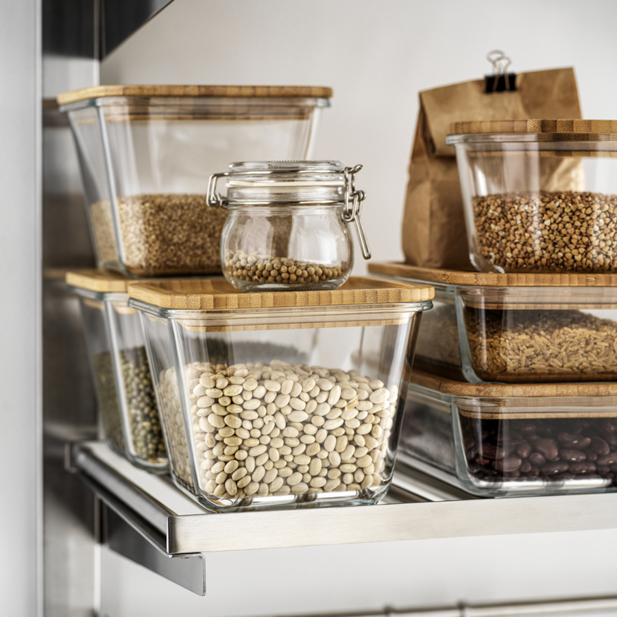 Glass food containers with wooden lids neatly storing dry goods on open kitchen shelves.