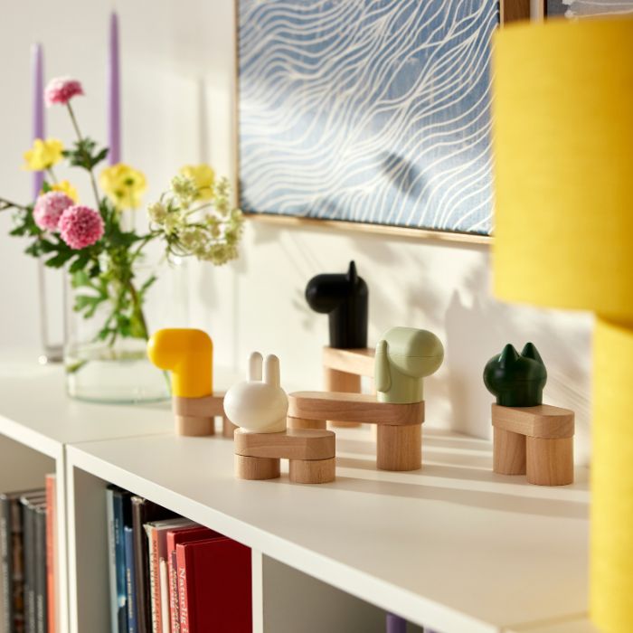 En una habitación luminosa, la luz del sol proyecta sombras en la pared desde un conjunto de bloques de construcción de juguete GREJSIMOJS que decoran una estantería.